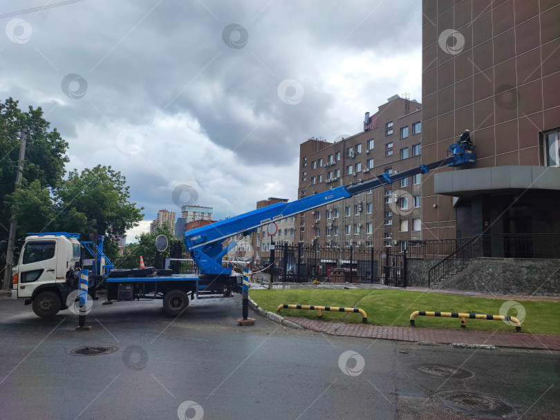 Скачать Ремонт фасада здания на высоте при помощи автомобильной вышки. Реконструкция фасада здания на высоте с использованием автомобильной вышки. фотосток Ozero