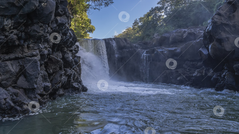 Скачать Красивый тропический водопад. Потоки воды падают с уступа в реку. фотосток Ozero