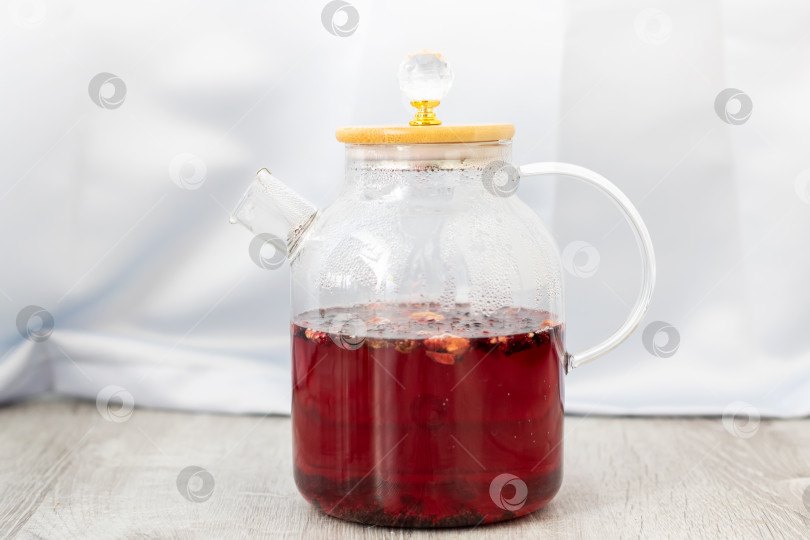 Скачать На деревянном столе стоит стеклянный чайник с красной жидкостью фотосток Ozero