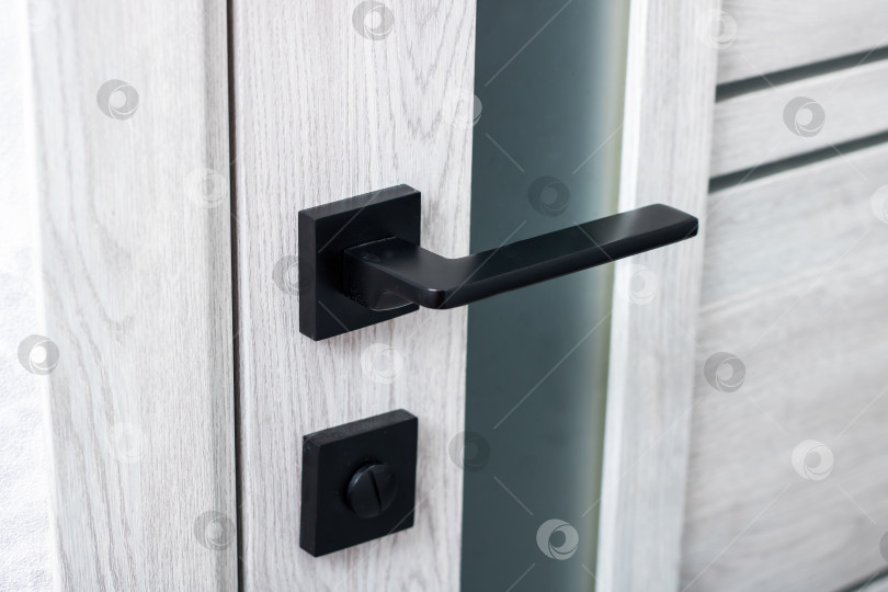 Скачать Детальный снимок крупным планом гладкой черной дверной ручки на белой двери фотосток Ozero