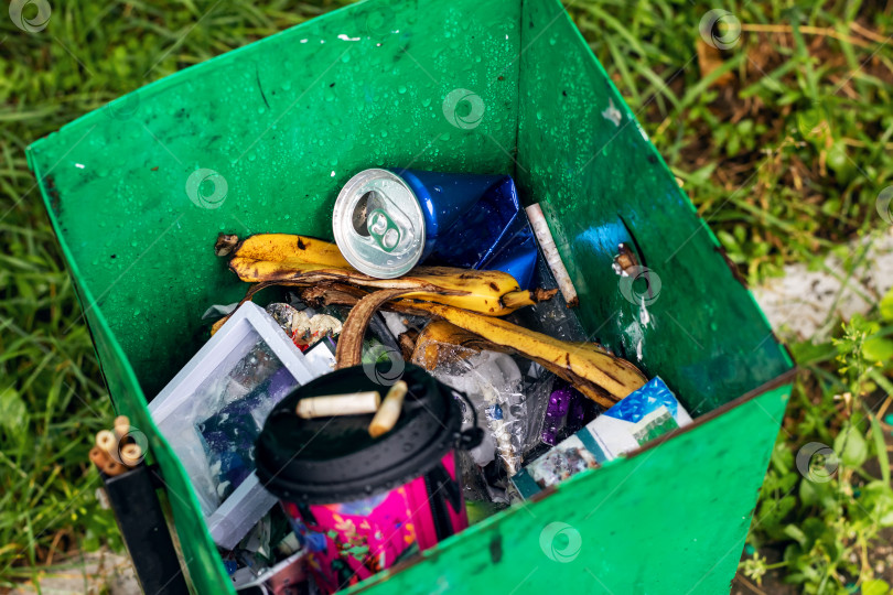 Скачать Ярко-зеленый мусорный бак, переполненный большим количеством мусора фотосток Ozero