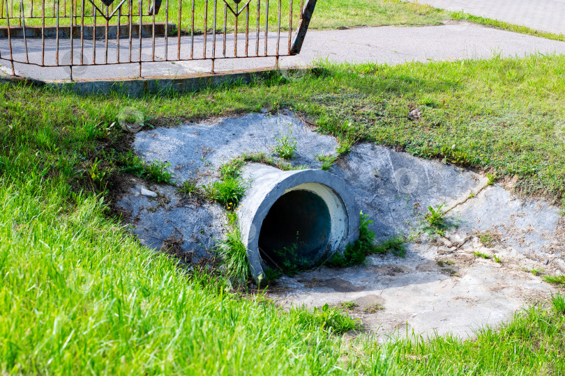 Скачать Большая бетонная труба лежит на траве прямо рядом с тротуаром фотосток Ozero