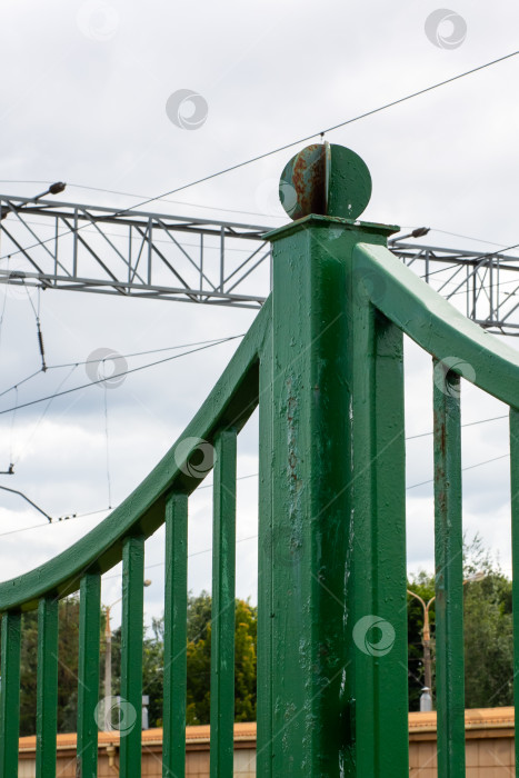 Скачать На заднем плане возвышается зеленый забор с металлической конструкцией фотосток Ozero