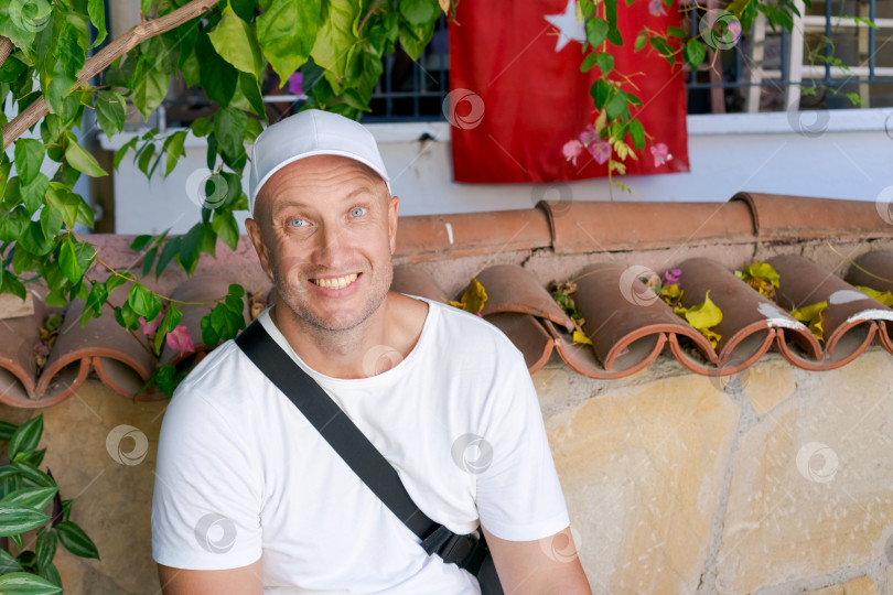 Скачать Мужчина в белой рубашке и шляпе сидит на стене фотосток Ozero