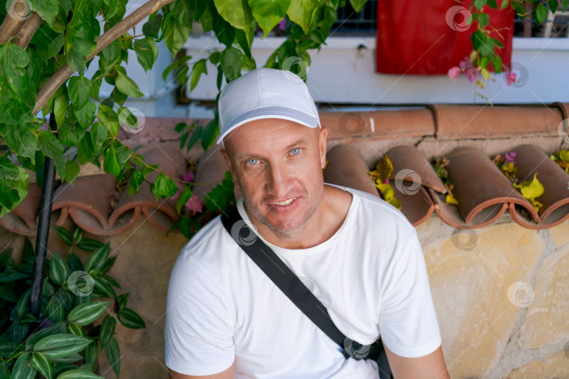 Скачать Мужчина в белой рубашке и шляпе сидит на каменной стене фотосток Ozero