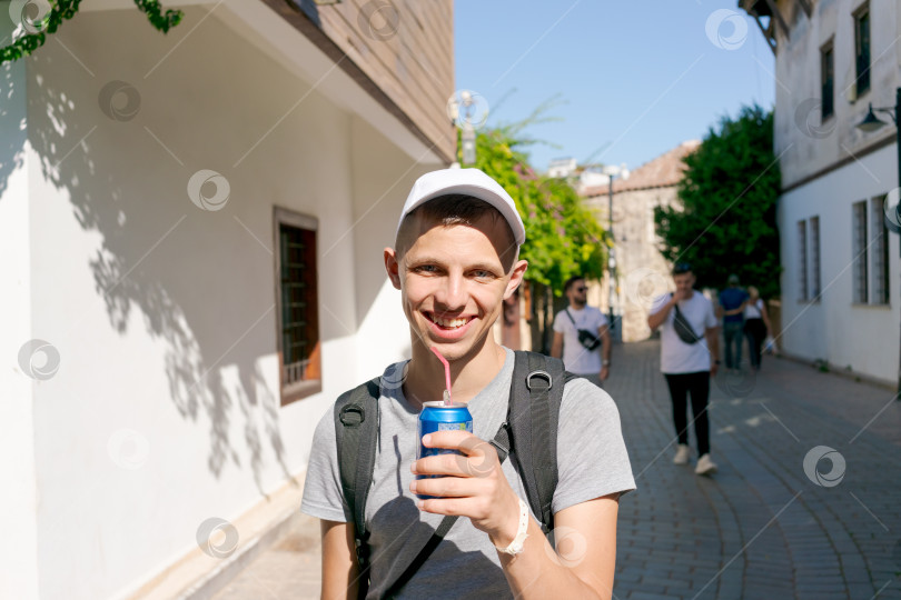 Скачать Молодой человек улыбается и держит в руках банку газировки фотосток Ozero