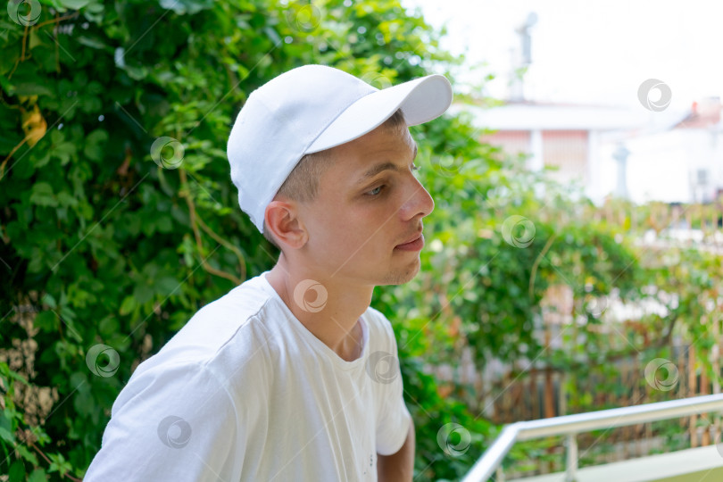 Скачать Мужчина в белой шляпе и белой рубашке сидит на перилах фотосток Ozero