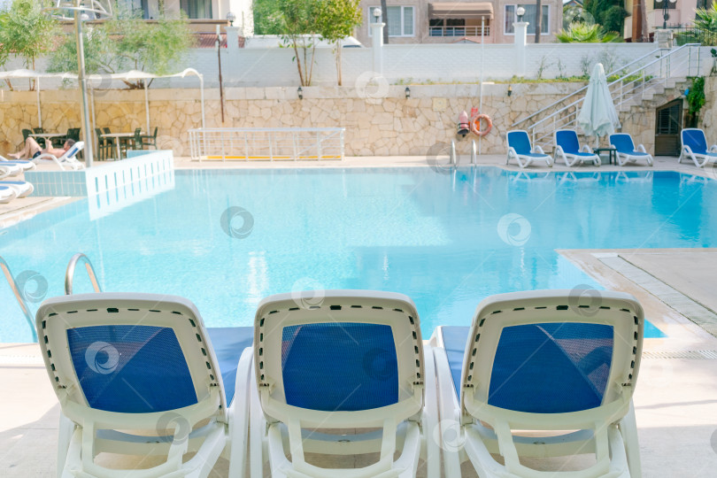 Скачать В зоне бассейна установлены три белых шезлонга фотосток Ozero