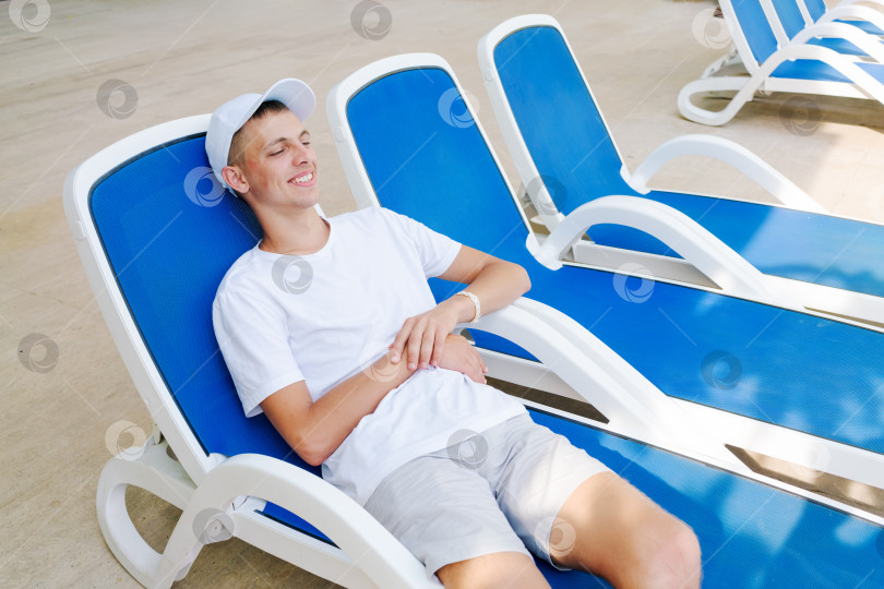 Скачать Молодой человек сидит в синем шезлонге фотосток Ozero