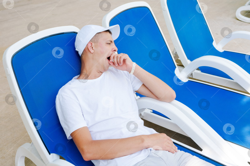 Скачать Мужчина спит в синем шезлонге фотосток Ozero