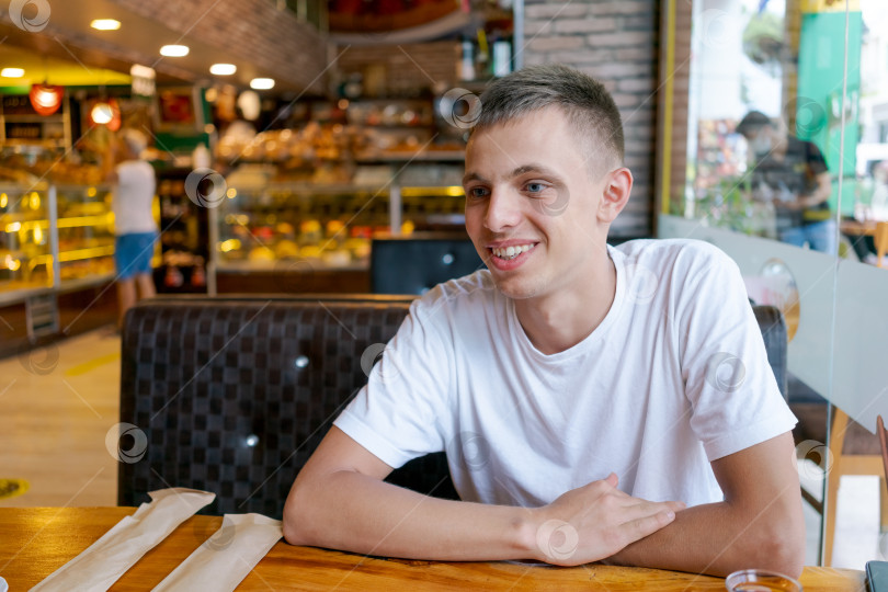 Скачать Молодой человек сидит за столиком в ресторане фотосток Ozero