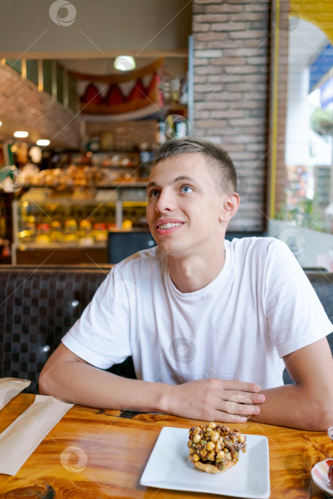 Скачать Мужчина сидит за столом, перед ним лежит выпечка фотосток Ozero