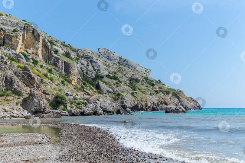 Скачать Каменистый пляж с утесом на заднем плане фотосток Ozero