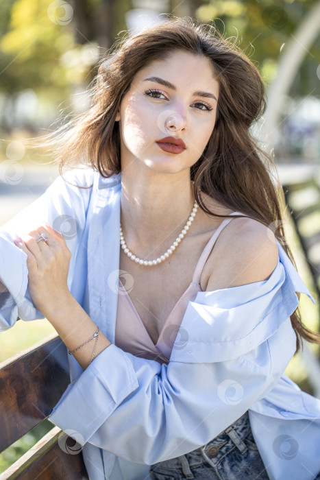 Скачать Молодая красивая женщина сидит на скамейке в осеннем парке фотосток Ozero