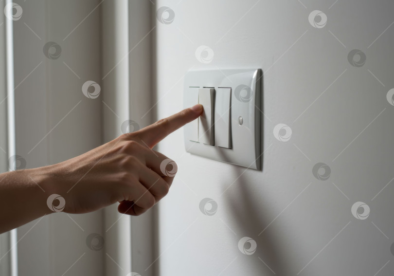 Скачать Женщина поворачивает выключатель на стене. Концепция экономии энергии и повседневной домашней рутины. Простое управление электричеством в домашних условиях. фотосток Ozero