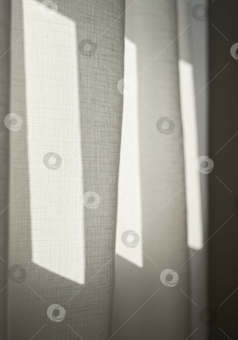 Скачать Естественный солнечный свет проникает сквозь легкие тканевые шторы, отбрасывая геометрические тени на текстурированный текстиль, создавая простой домашний фон или дизайн для повседневного домашнего интерьера. фотосток Ozero