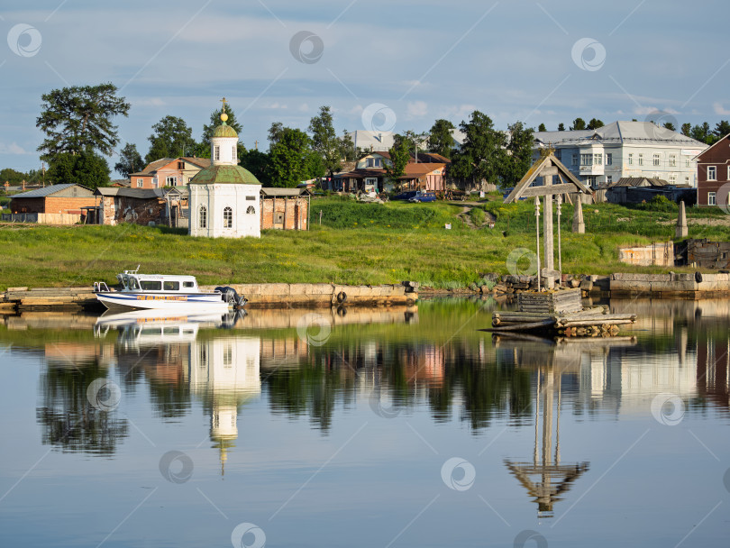 Скачать Деревянный поклонный крест на воде в бухте Благополучия Соловецкого острова. На берегу Петропавловская часовня, дома и хозяйственные постройки поселка. фотосток Ozero