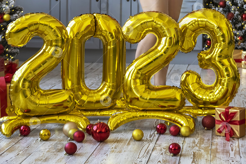 Скачать Крупный план золотых шаров в виде цифр 2023 на фоне рождественской елки, стоящей в студии. Люди празднуют новый год, ждут, предвкушают. Концепция нового года и празднования. фотосток Ozero