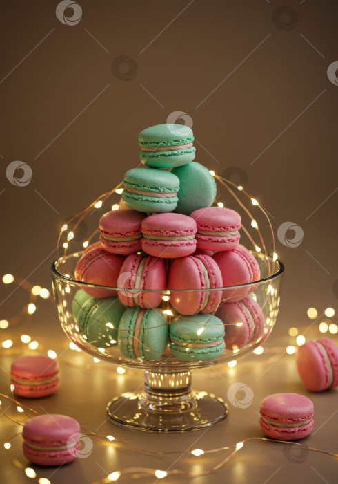 Скачать Розовые и бирюзовые макароны выложите пирамидкой в стеклянную вазочку, украшенную гирляндами. Элегантный десерт для торжества или вечеринки. фотосток Ozero