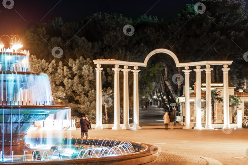 Скачать город Геленджик, Краснодарский край, Россия, 7 ноября 2024 года. Набережная курорта Геленджик вечером. Поющий фонтан. На заднем плане - арка с колоннами. фотосток Ozero