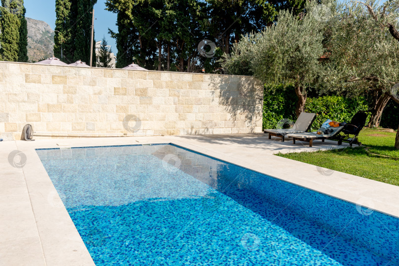 Скачать Открытый бассейн с голубой водой на заднем дворе загородного дома-коттеджа фотосток Ozero