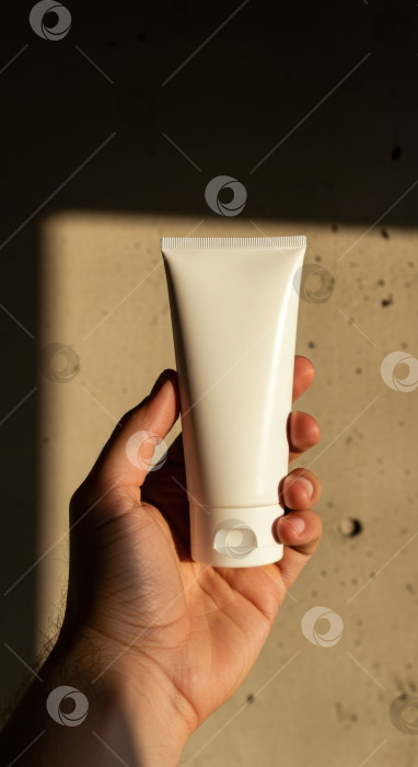 Скачать Мужчина держит в руках фирменную упаковку крема для мужчин. Белый тюбик средства по уходу за кожей. Косметика для мужчин beauty. фотосток Ozero