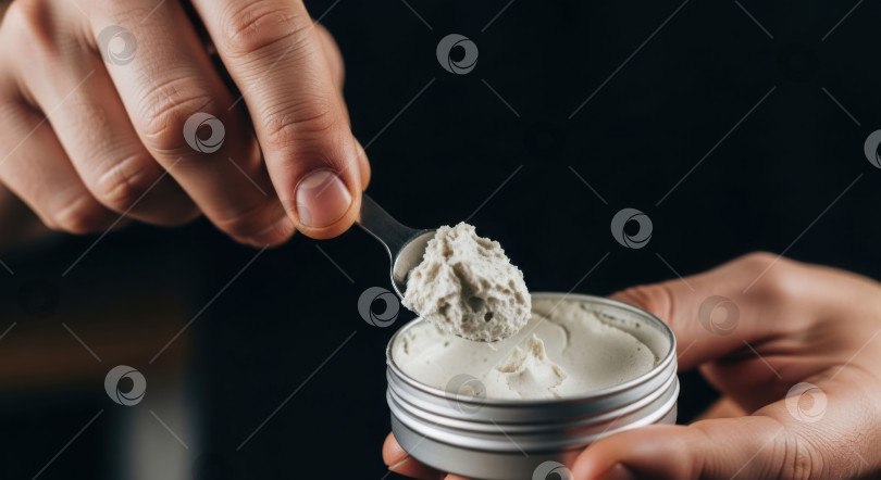 Скачать Мужчина держит банку со средством для укладки волос и ложку с бальзамом. Концепция ухода за волосами и мужскими косметическими принадлежностями. Мужской уход. фотосток Ozero