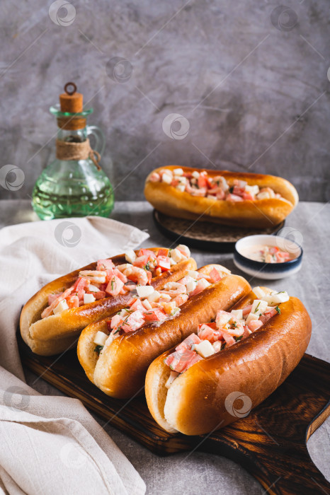Скачать Вкусные хот-доги в обжаренных булочках с салатом из помидоров, яиц и креветок, вид сверху фотосток Ozero