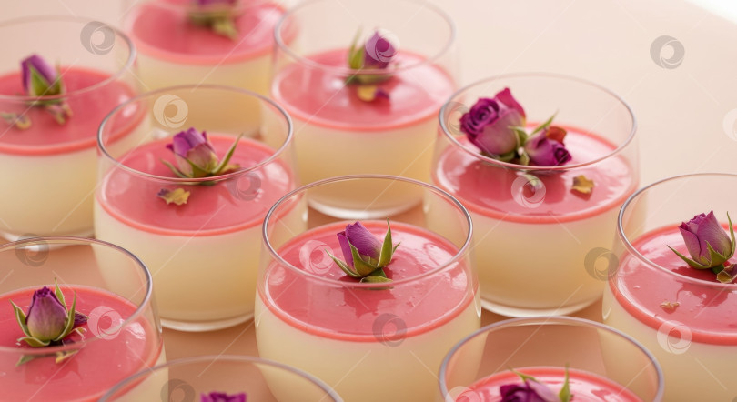 Скачать Ряды элегантных десертов панна котта с нежной розовой начинкой и украшением в виде бутонов роз. фотосток Ozero
