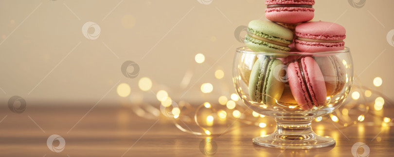 Скачать Стопка разноцветных французских макарон в стеклянной миске с гирляндами. фотосток Ozero