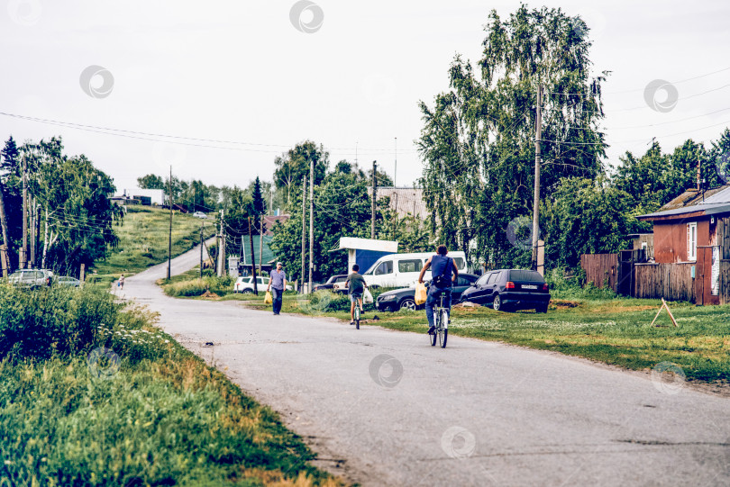 Скачать Белокуриха, Россия, 28 июня 2017 года, Сельский житель проезжает на велосипеде по разбитой дороге в бедной деревне фотосток Ozero