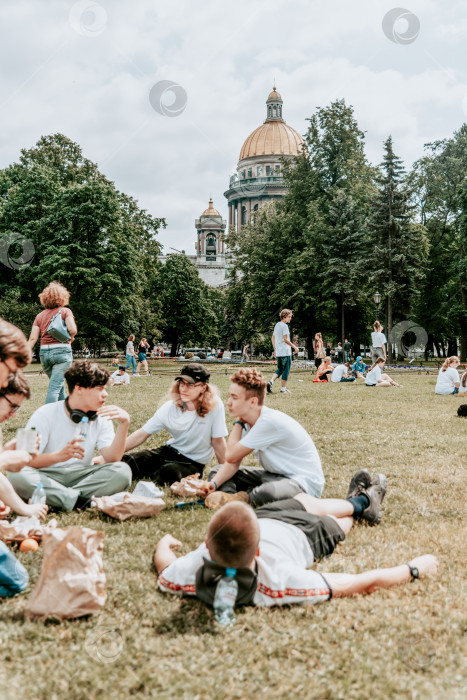 Скачать Санкт-Петербург, Россия, 2 июля 2020 года, Люди-подростки на пикнике, сидят на лугу, Исаакиевский собор на заднем плане фотосток Ozero
