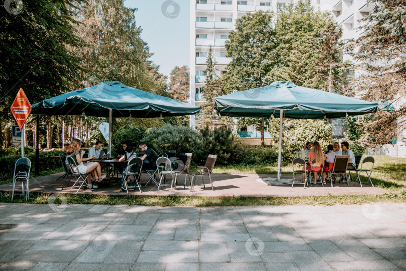 Скачать Санкт-Петербург, Россия, 18 июня 2021 года, люди сидят летом на террасе уличного ресторана в парке фотосток Ozero