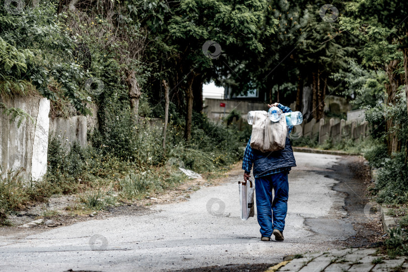 Скачать Стамбул, Турция, 8 мая 2018 года, Мужчина несет пустые пластиковые бутылки и идет по улице фотосток Ozero