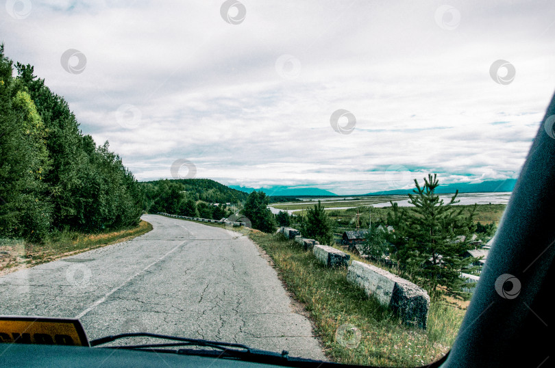 Скачать Вид из переднего окна автомобиля на асфальтированную разбитую пригородную дорогу шоссе фотосток Ozero