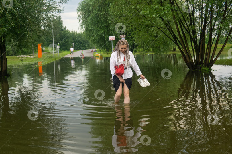 Скачать женщина переходит лужу в затопленном парке в дождливый день фотосток Ozero