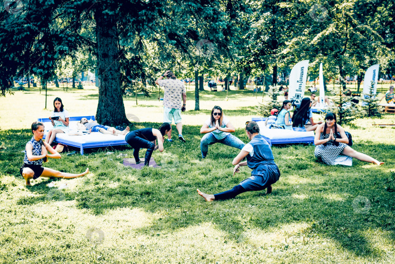 Скачать Санкт-Петербург, Россия, 27 июля 2019 года, Группа людей занимается йогой на открытом воздухе в парке фотосток Ozero