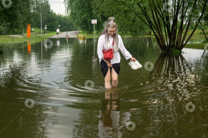 Скачать женщина переходит лужу в затопленном парке в дождливый день фотосток Ozero