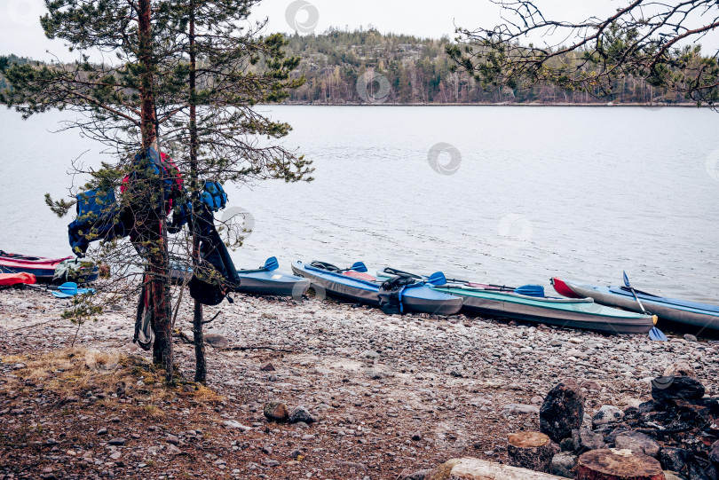 Скачать Каяк, лежащий на берегу спокойного озера в пасмурный день, на фоне лесных деревьев и воды фотосток Ozero