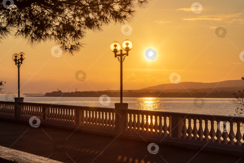 Скачать Курорт Геленджик. Набережная на закате. Балюстрада и набережная в косых лучах заходящего солнца. Кавказские горы на заднем плане. фотосток Ozero