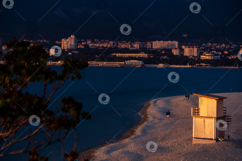 Скачать Курорт Геленджик. Пляж Геленджик-Бужта на закате. Люди прогуливаются по пляжу. Будка спасателя на берегу. фотосток Ozero