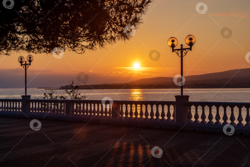 Скачать Курорт Гелекник. Набережная на закате. Солнце светит сквозь балюстраду, которая отбрасывает тень на набережную. фотосток Ozero