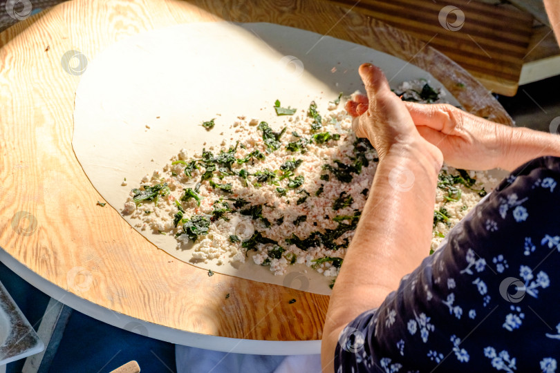 Скачать Женщина готовит блюдо со шпинатом на деревянном столе фотосток Ozero