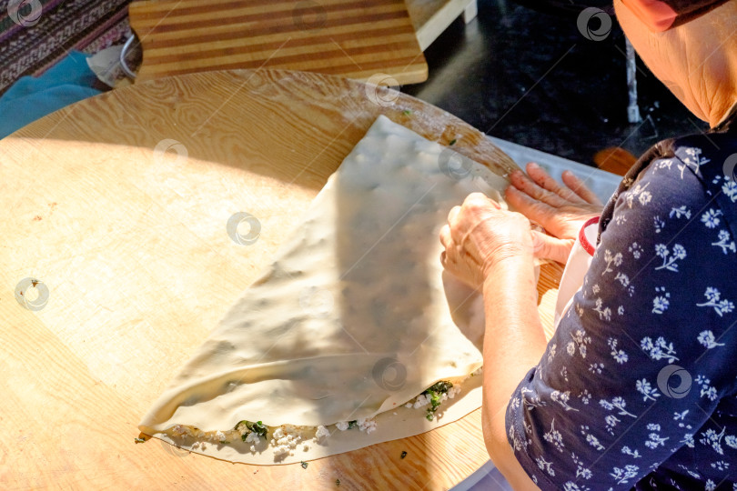 Скачать Женщина раскатывает тесто на столе фотосток Ozero