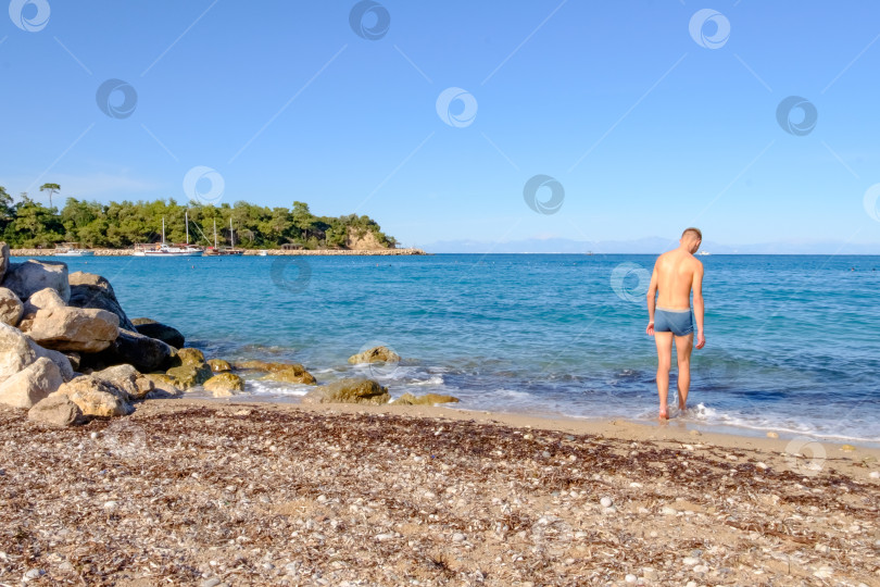 Скачать Мужчина стоит на пляже фотосток Ozero