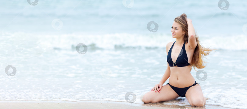 Скачать Женщина сидит на пляже в черном бикини фотосток Ozero