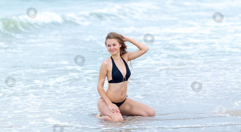 Скачать Женщина сидит в воде в черном бикини фотосток Ozero