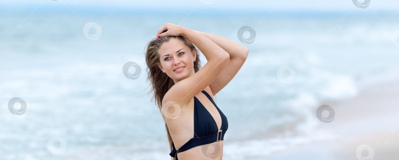 Скачать Женщина стоит на пляже в черном бикини фотосток Ozero