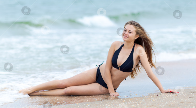 Скачать Женщина лежит на пляже в черном бикини фотосток Ozero