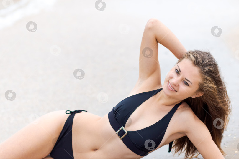 Скачать Женщина лежит на пляже в черном бикини фотосток Ozero